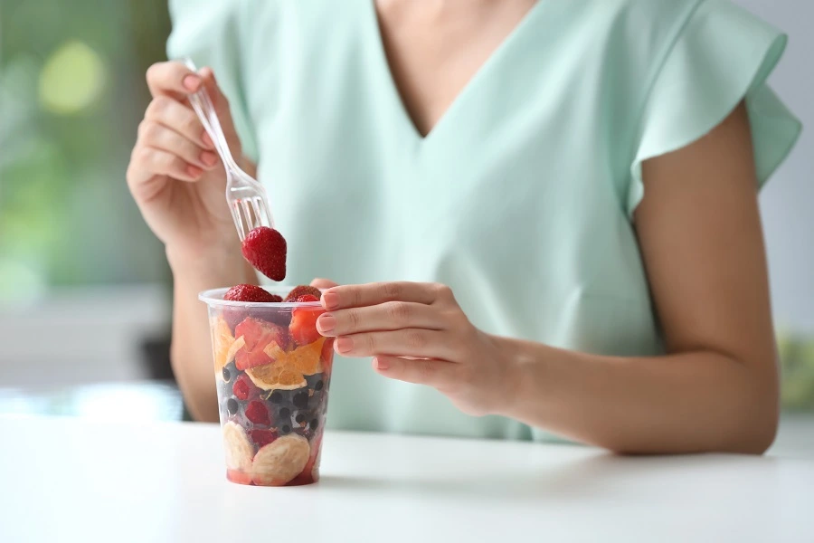 woman's hand holding transparent glass of fruits